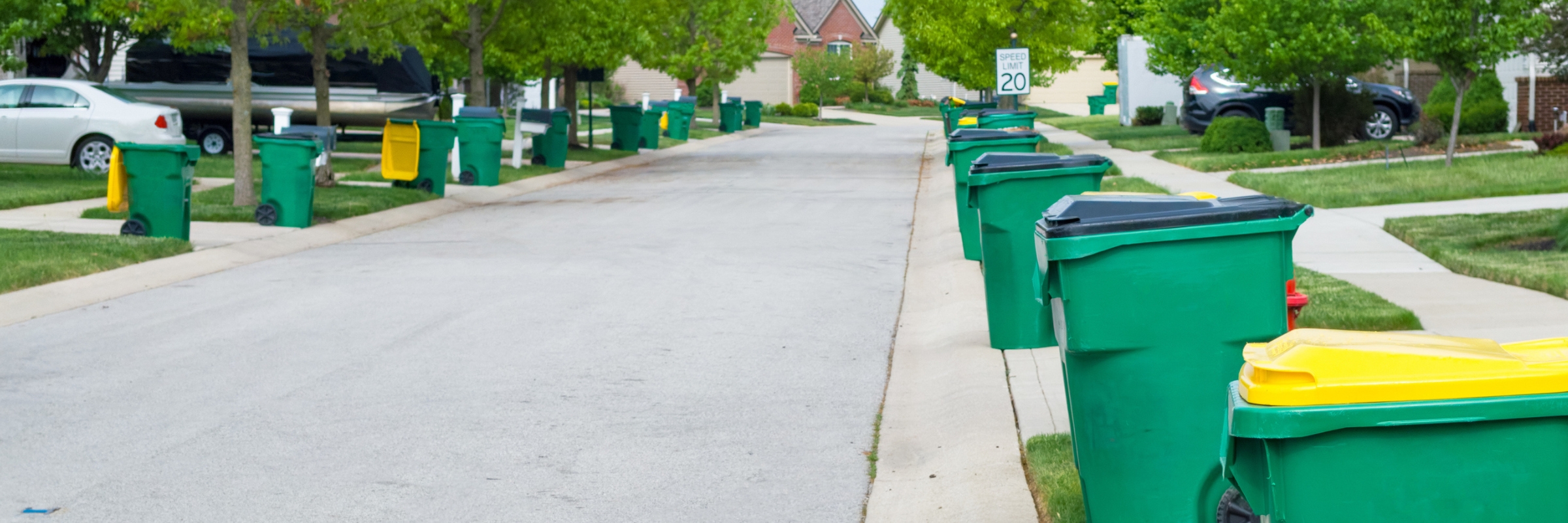 Green trash cans lined up on residential street